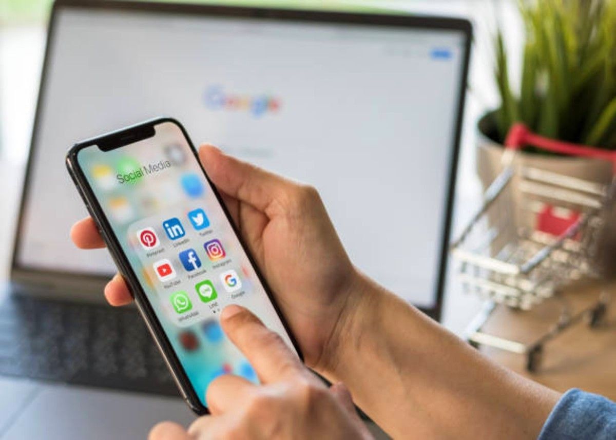 a person holding his phone while showing socia media apps on the screen