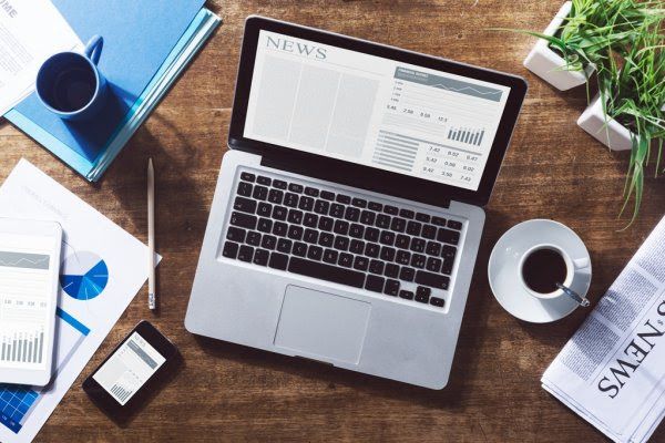 aerial view of a table with laptop, coffee, and newspaper above it